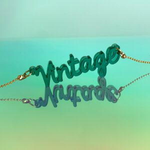 goudkleurige ketting met een doorzichtige donker groene hanger die Vintage zegt